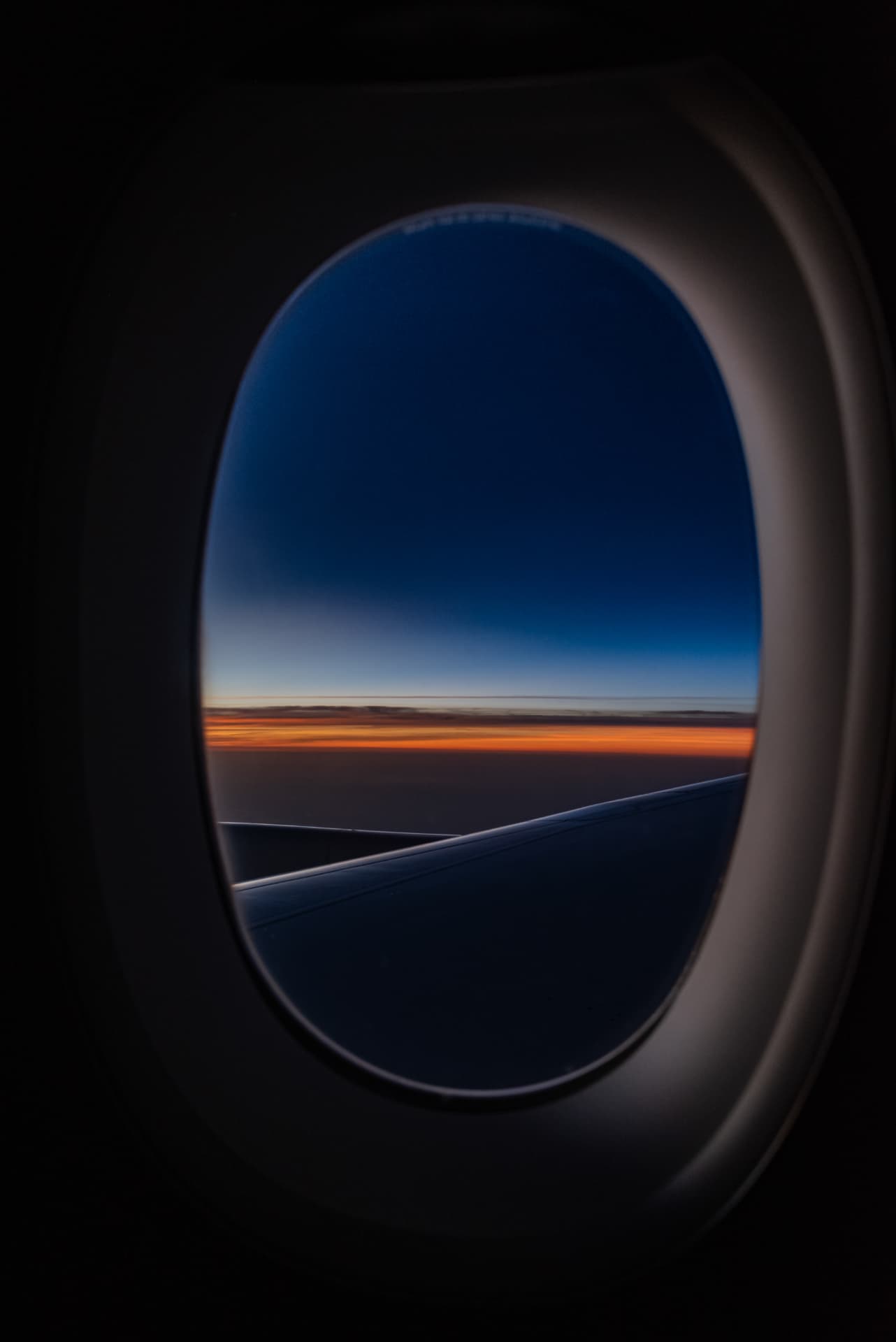 Dusk horizon and wing seen through an airplane window