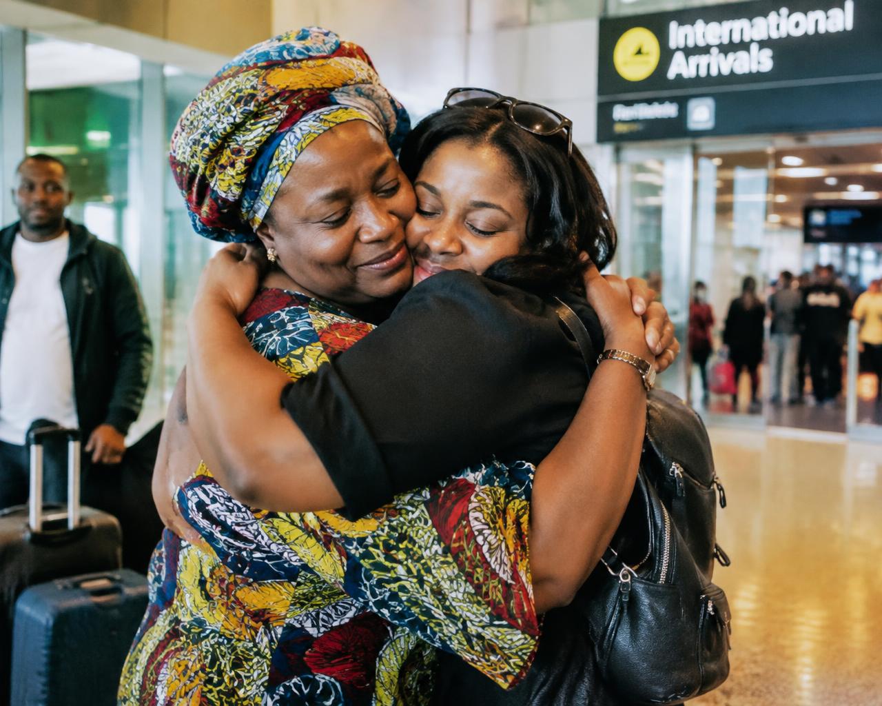 A mother and daughter embracing at international arrivals